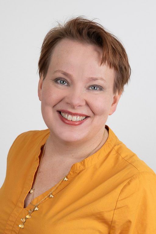 Pietiläinen on pukeutunut keltaiseen paitaan ja hymyilee kameralle..